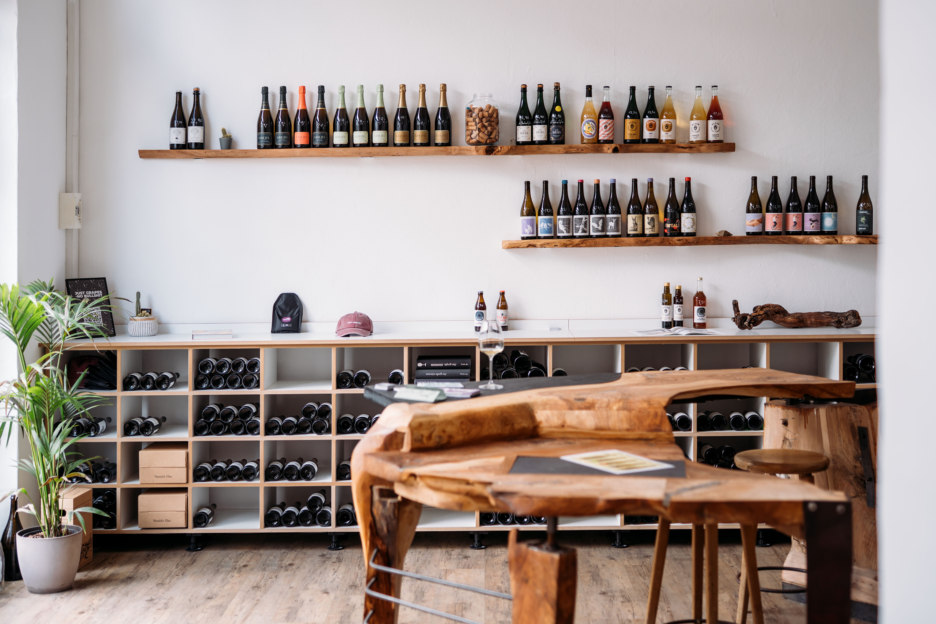 Innenansicht des Just Grapes Stores in Kassel mit Holzregalen voller Naturweine und einer hellen, modernen Einrichtung.